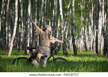 50 years old woman at bicycle with alsatian dog