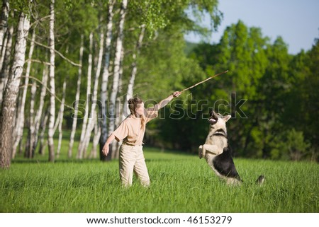 50 years old woman playing with alsatian dog on grass