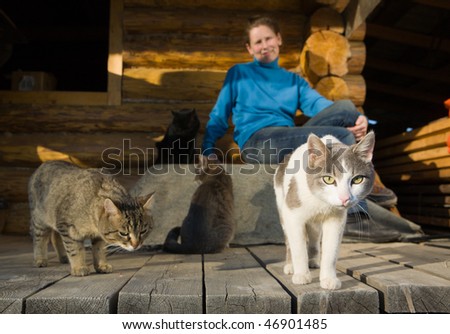 Woman with her cats sitting near her country house