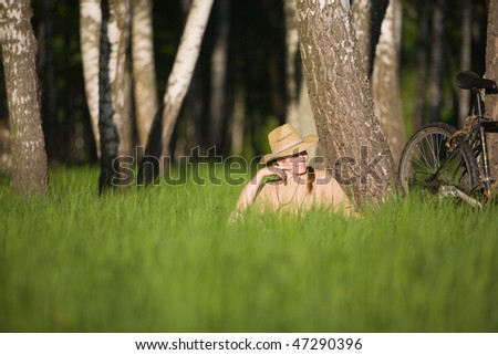 50 years old woman in straw hat with bicycle in  birch forest at summer