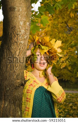 Young beautiful homely woman with crown of maple leaves in autumn park