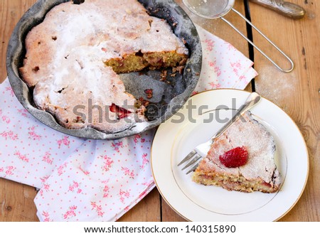 Slice of strawberry cake on the plate and the cake in the tin