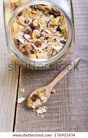 Muesli mix in a jar and on spoon on wooden table
