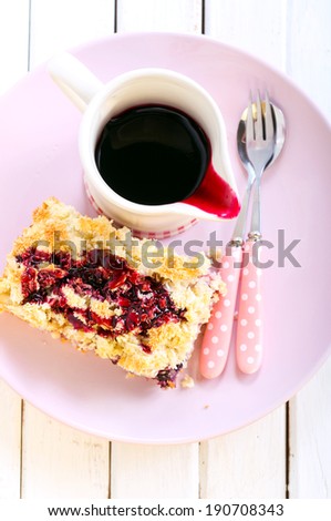 Mixed berry and fruit cake with coconut and almond topping and sauce in a jar, selective focus
