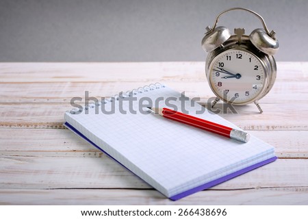Time management concept: vintage alarm clock, pencil and notepad