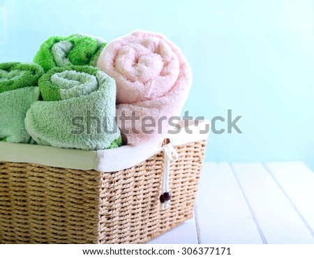 Different colors towels  in wicker basket over light background