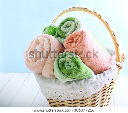 Different colors towels  in wicker basket over light background