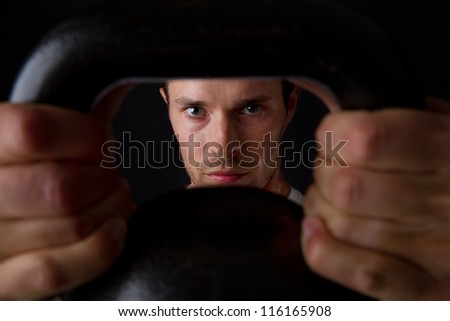 Closeup portrait of young man lifting kettle bell