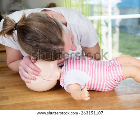 Woman performing CPR on baby training doll, checking for signs of breathing