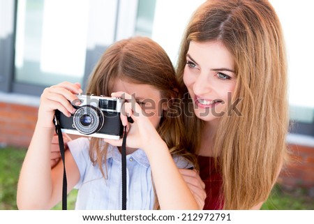 Little girl and her mother or sister shooting with a vintage camera