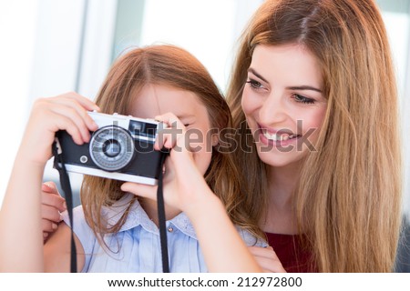 Little girl and her mother or sister shooting with a vintage camera