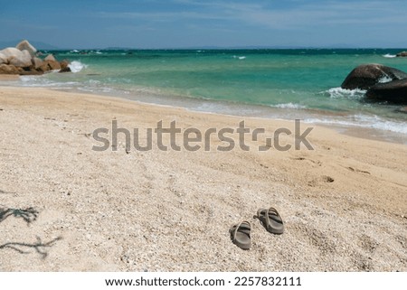 Flip flops on sand beach with stone arch and turquoise sea against blue sky in Ko Man Klang, Rayong, Thailand. Stock fotó © 