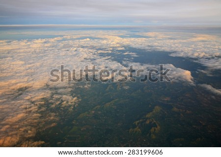 View of clouds from the window of aircraft. Flying above the clouds at sunrise