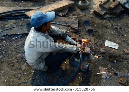 NAGPUR, MAHARASHTRA, INDIA - MAR 27: Unidentified Welders in their workshop cutting the pieces of iron for melting on Mar 27, 2014 in Nagpur, India.