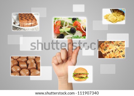 Woman hand uses touch screen interface with food on grey backround