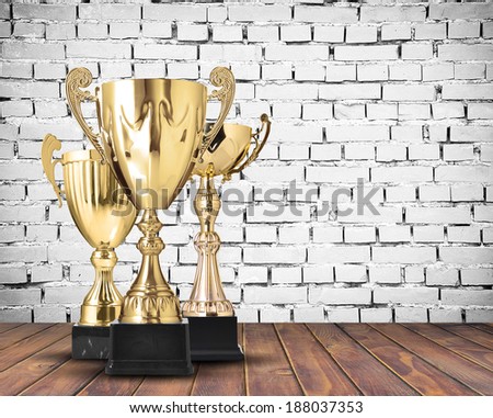 Golden cup trophies on white brick wall