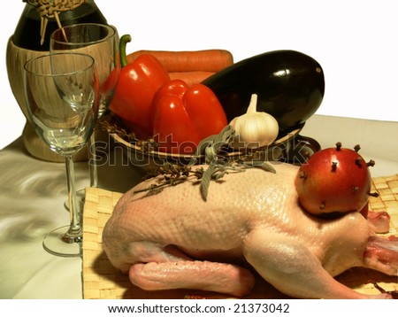 Duck prepared to bake in an oven with vegetables, wine, glasses