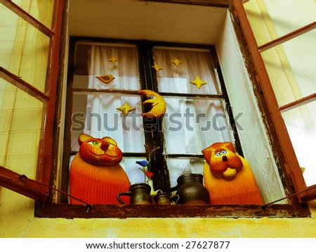 Two wooden cats and vases against an old window