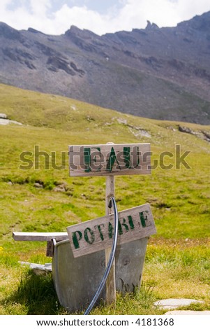 Drinking-water fountain in the mountains with sign wich says \