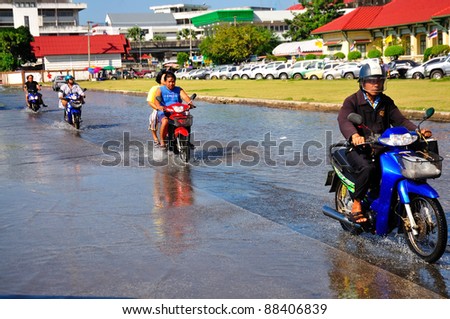 CHACHOENGSAO, THAILAND - OCTOBER 29:  Unidentified citizens on motorbikes ride through flood waters from the rising tide that overflowed onto roads, market and houses on October 29, 2011 in Chachoengsao,Thailand.