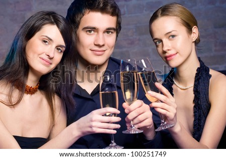 Two young beautiful women and man with champagne at party