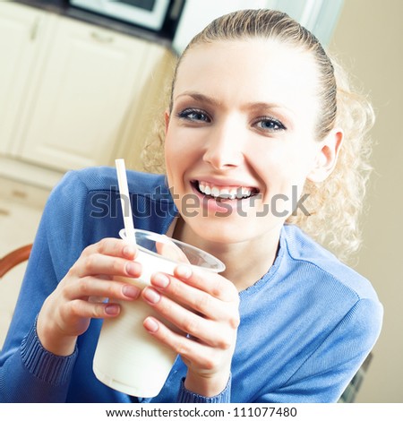Cheerful woman drinking milk, indoors