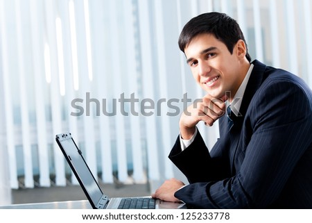 Portrait of successful happy smiling business man working with laptop at office, with copyspace