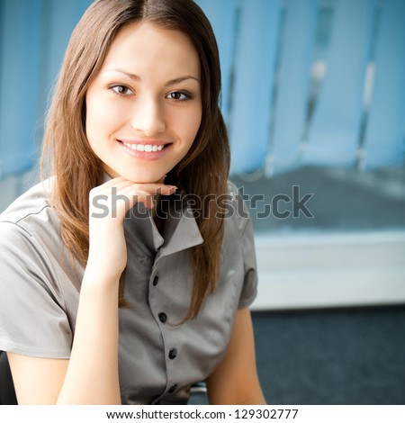 Young happy smiling cheerful business woman at office, with copyspace
