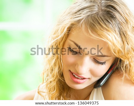Portrait of young happy smiling woman talking on cellphone