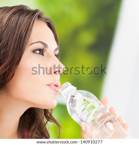 Portrait of young woman drinking water from bottle, outdoors
