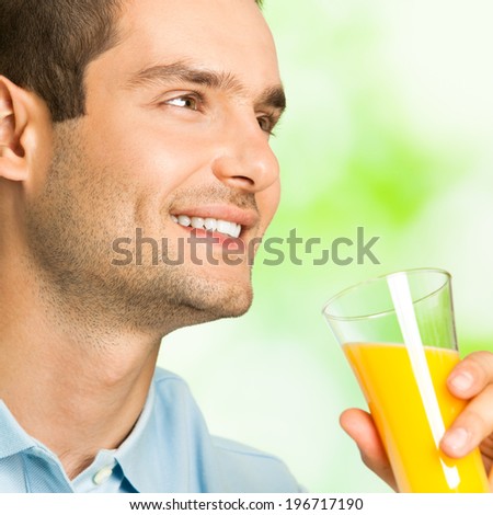 Young smiling man with orange juice, outdoors