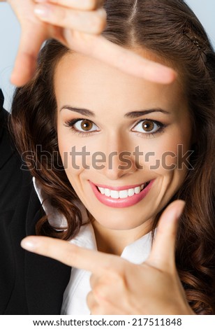 Portrait of young happy smiling business woman framing her face with hands, over blue background