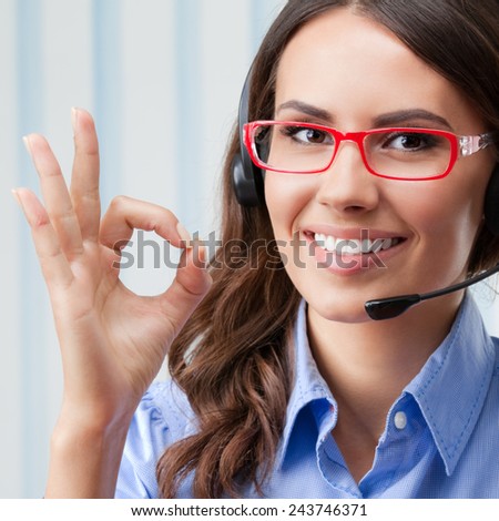 Portrait of happy smiling cheerful young support phone operator in headset, showing okay gesture, at office