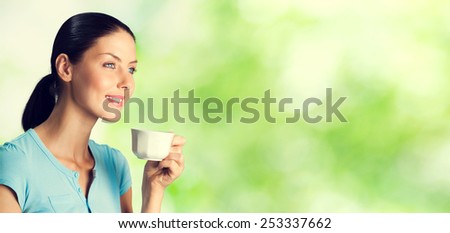 Portrait of smiling young woman drinking coffee, outdoor, with blank copyspace area for text or slogan