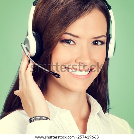 Portrait of happy smiling cheerful customer support phone operator in headset, on green background