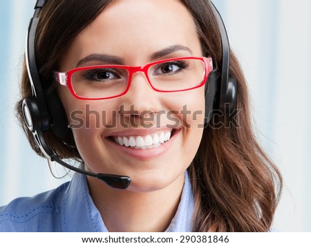 Portrait of happy smiling cheerful beautiful young female support phone operator in headset and glasses, at office. Customer assistance service concept.
