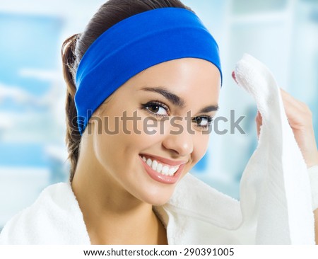 Portrait of happy smiling young woman in fitness wear with towel, at gym. Beauty and health concept.