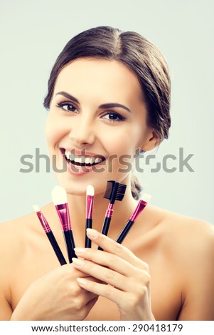 Young happy smiling woman with cosmetics make up tools. Visage and beauty concept.