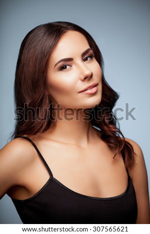 portrait of beautiful young woman in black tank top clothing, on grey background