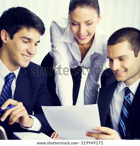 Three young businesspeople working with document at office, teamwork concept