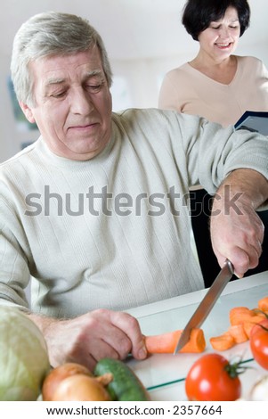 Elderly happy couple cooking at kitchen