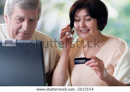 Happy elderly couple on laptop, shopping in internet shop or making card verification
