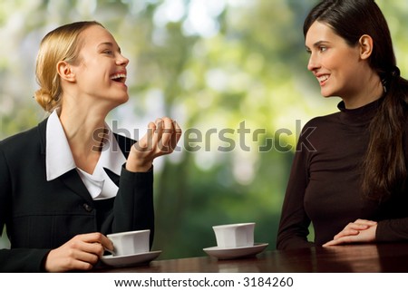 Two smiling attractive young business women chatting on coffee break, outdoor