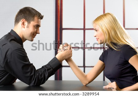 Young attractive couple or business people fighting in arm-wrestling