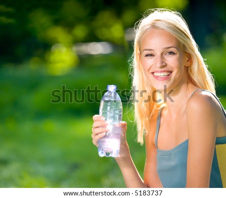 Young woman with bottle of water outdoors. To provide maximum quality I have made this image by combination of two photos.