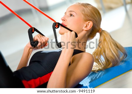 Young woman doing fitness exercises with expander at home