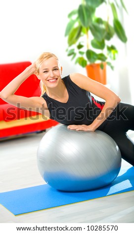 Young happy woman doing fitness exercises at home