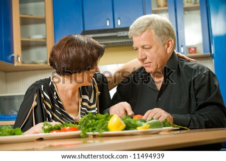 Elderly happy attractive smiling couple cooking at kitchen