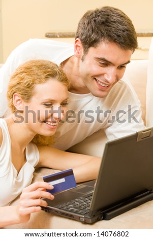 Young happy couple paying by credit card in internet shop