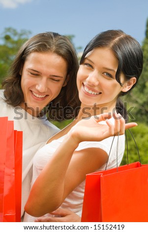 Young happy amorous couple with red shopping bags outdoors